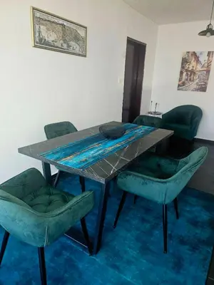 a dining room table with green chairs and a table with at Apartman Mateo in Cetinje