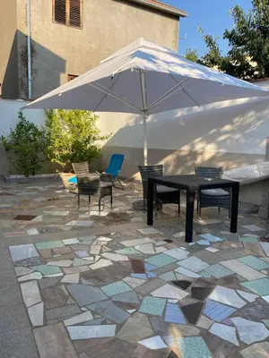 a table and chairs under an umbrella on a patio at Apartmani Sutomore welcome in Sutomore
