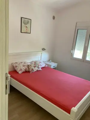 a bedroom with a bed with red sheets and a window at Apartmani Sutomore welcome in Sutomore