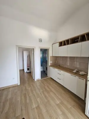 an empty kitchen with white cabinets and wooden floors at Apartmani Sutomore welcome in Sutomore