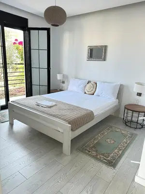 a white bedroom with a large bed and a rug at Carpe Diem 1 in Ulcinj