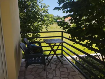 a table and chairs on a balcony with a view of a field at Cottage in nature of Cetinje in Cetinje