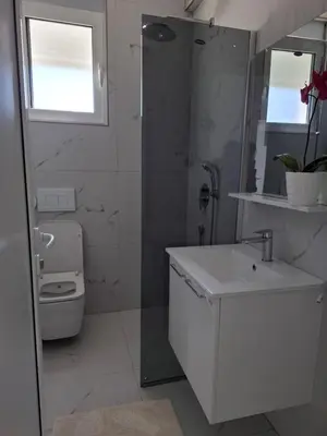 a white bathroom with a sink and a toilet at Vila stockholm in Donji Štoj