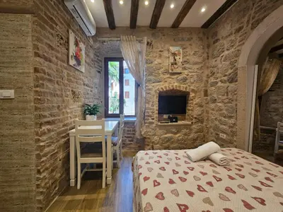 a bedroom with a bed and a table and a tv at patrik in Kotor