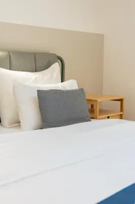 a white bed with white pillows and a table at Casa Campana in Kotor