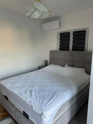 a white bed in a bedroom with a white wall at DD apartment in Budva
