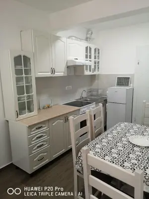 a kitchen with white cabinets and a table with chairs at Apartman Bucan in Ulcinj