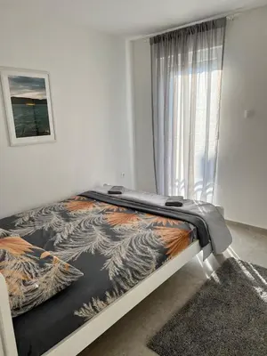 a bed in a white room with a window at A&A apartments in Kravlja