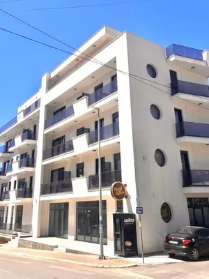a white building with a car parked in front of it at Amd Apartmani in Dobra Voda