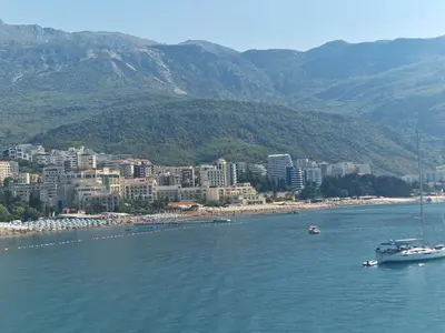a boat in a body of water with a city at Skyline lux apartman Becici sa pogledom na more in Budva