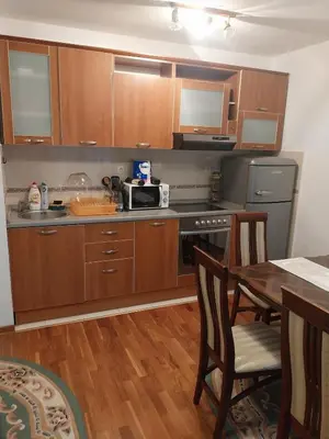 a kitchen with wooden cabinets and a table with a microwave at Apartman Elena Budva in Budva
