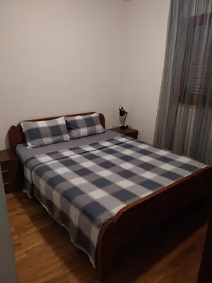 a bedroom with a bed with a blue and white checkered blanket at Apartman Elena Budva in Budva