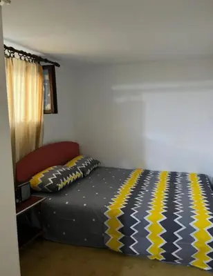 a bedroom with a bed with a yellow and blue blanket at Apartman centar in Podgorica