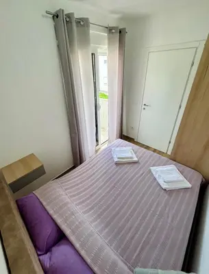 a bedroom with a bed with purple sheets and a mirror at Apartman Živaljević 1 Tivat in Tivat