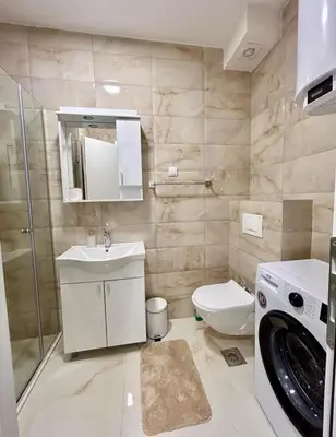 a bathroom with a toilet sink and a washing machine at Apartman Živaljević 1 Tivat in Tivat