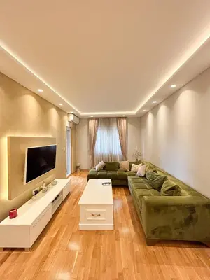 a living room with a green couch and a television at Modern 1-bedroom apartment M25 in Podgorica