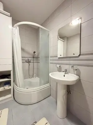 a white bathroom with a shower and a sink at Modern 1-bedroom apartment M25 in Podgorica