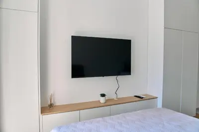 a bedroom with a tv on a white wall at Studio GRIGÓ in Budva