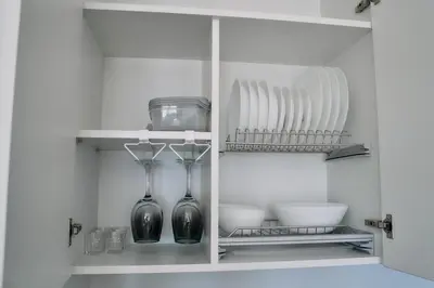 a white cabinet with two vases and plates in it at Studio GRIGÓ in Budva