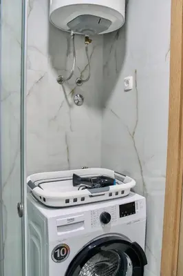 a white washing machine in a room with a lamp at Studio GRIGÓ in Budva
