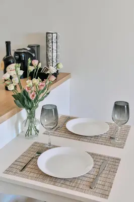two white plates on a table with glasses and flowers at Studio GRIGÓ in Budva