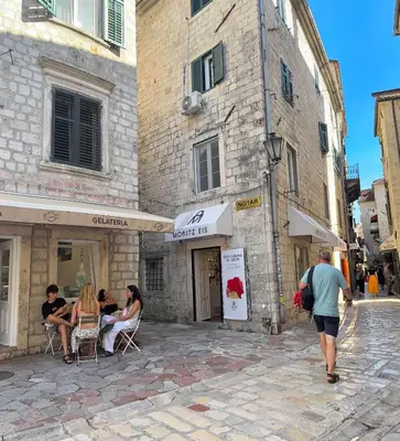 a group of people sitting in chairs outside of a building at Apartman HOME Kotor in Kotor