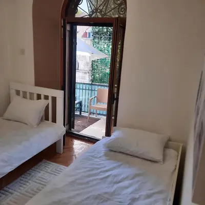 two beds in a room with a view of a balcony at Apartman HOME Kotor in Kotor