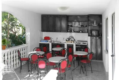 a kitchen with red chairs and tables in a kitchen at Apartmani Ulcinj Mirza in Ulcinj