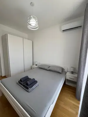 a bedroom with a large bed with a white wall at Tre Sorelle Becici in Becici