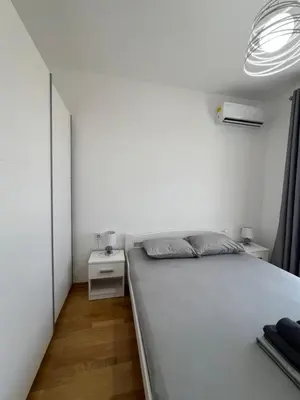 a white bedroom with a bed and a night stand at Tre Sorelle Becici in Becici