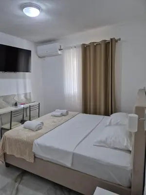 a bedroom with a large bed and a desk at Apartmani Nevena Airport in Mitrovići