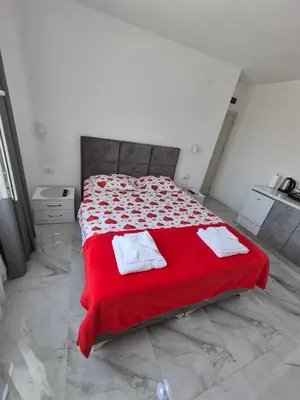 a bedroom with a red bed with two towels on it at Apartmani Nevena Airport in Mitrovići