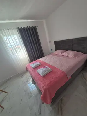 a bedroom with a bed with pink sheets and a window at Apartmani Nevena Airport in Mitrovići