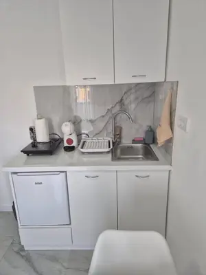 a kitchen with white cabinets and a sink at Apartmani Nevena Airport in Mitrovići