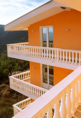 an orange house with white railings and a balcony at Vila Kraljica Snežna in Kravlja