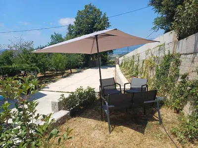 two chairs and an umbrella in a yard at Apartment Brijest-Kotor in Kotor