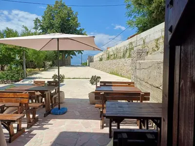 a patio with wooden tables and an umbrella at Apartment Brijest-Kotor in Kotor