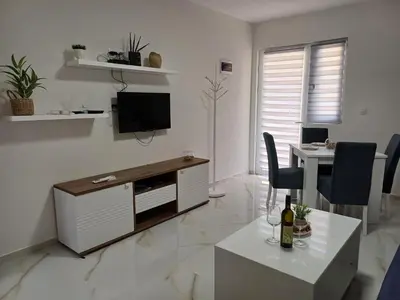 a white living room with a tv and a desk at Apartment Brijest-Kotor in Kotor