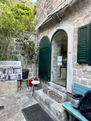 a stone building with green doors and a table at sar 6 in Kotor