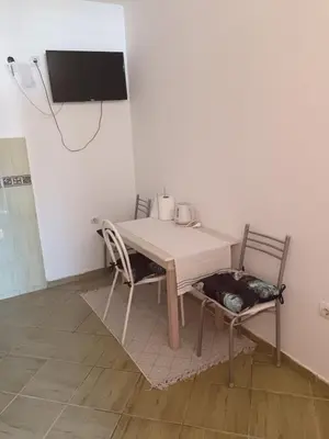 a table with two chairs and a tv on a wall at Pet Friendly Apartment Ground Floor in Petrovac na Moru