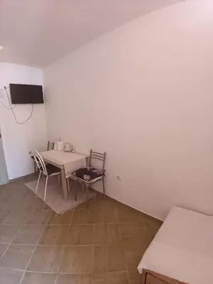 a room with a table and a chair and a television at Pet Friendly Apartment Ground Floor in Petrovac na Moru