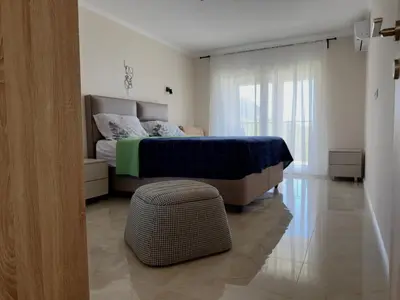 a bedroom with a bed and a ottoman in the foreground at Sunset Serenade Apartment
