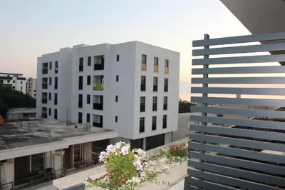 a white apartment building with flowers on the balcony at AMD - garsonjera 312 in Dobra Voda