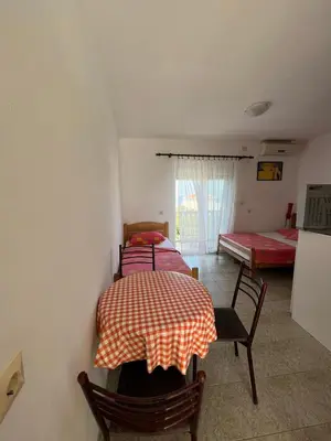 a room with two beds and a table and chairs at Apartmani MiS in Dobra Voda