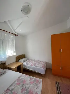 a bedroom with two beds and a cabinet and a window at Apartmani MiS in Dobra Voda