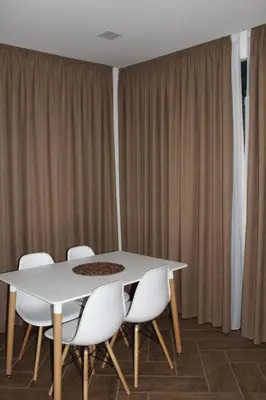 a white table and chairs in a room with curtains at AMD - stan 314 in Dobra Voda