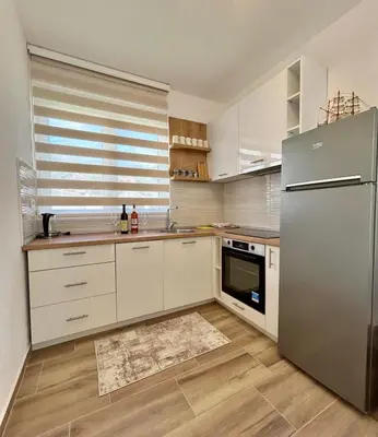 a kitchen with white cabinets and a stainless steel refrigerator at Apartman Živaljević 3 Tivat in Tivat
