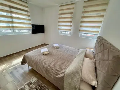 a bedroom with a bed and two windows at Apartman Živaljević 3 Tivat in Tivat