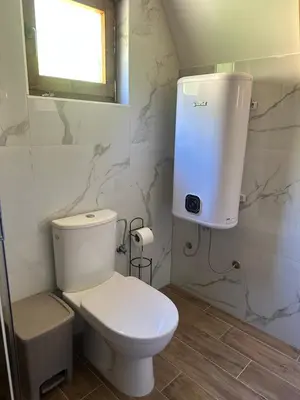 a bathroom with a white toilet and a window at Valley Nest in Virpazar