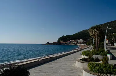 a sidewalk next to the water with a beach at Studio Apartman Stefana in Kravlja